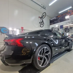 Audi, musta coupé-sedan — takaviisto, peilimäinen heijastus työvaloissa